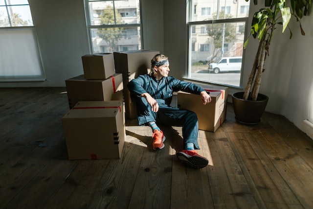 a person sitting in the sun surrounded by moving boxes